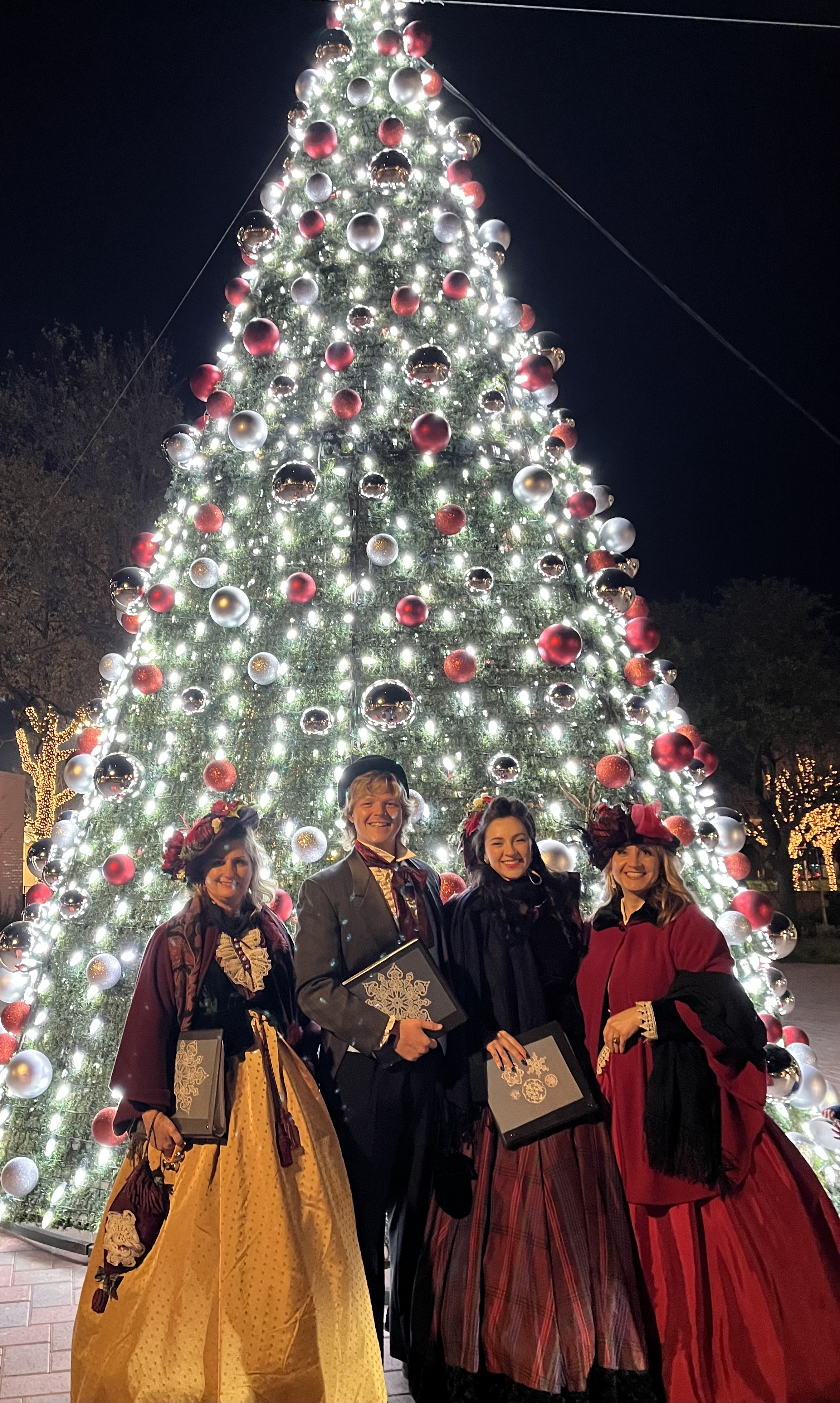 Carolers in front of Christmas tree